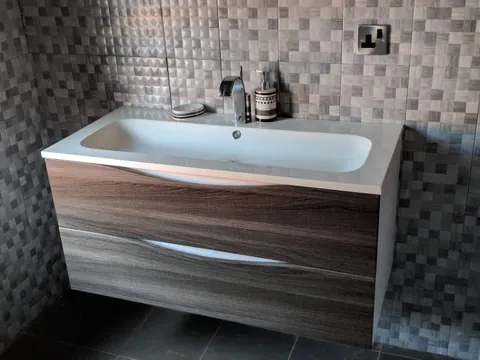 Newly installed wall-hung vanity basin with mixer tap in a tiled bathroom