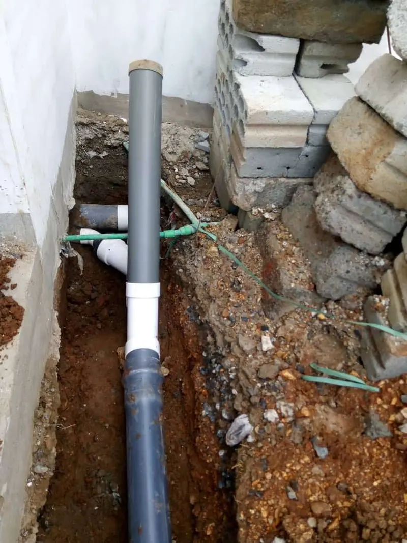 Grey waste pipe connection being made in an excavated trench