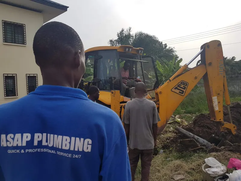 ASAP Plumbing team member watching an excavator dig a drainage trench