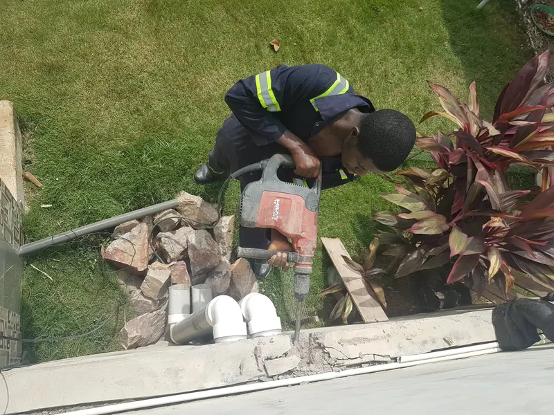 Technician cutting into a garden surface to lay an external pipe run
