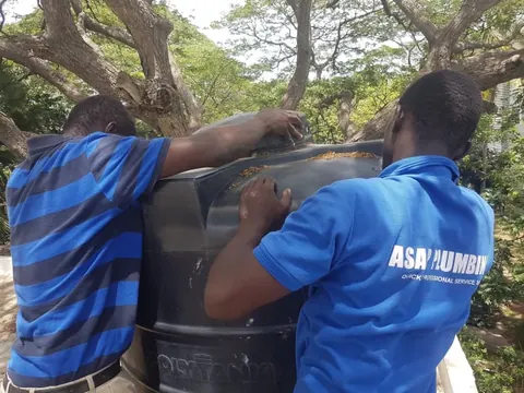 Two ASAP Plumbing technicians positioning a large water storage tank